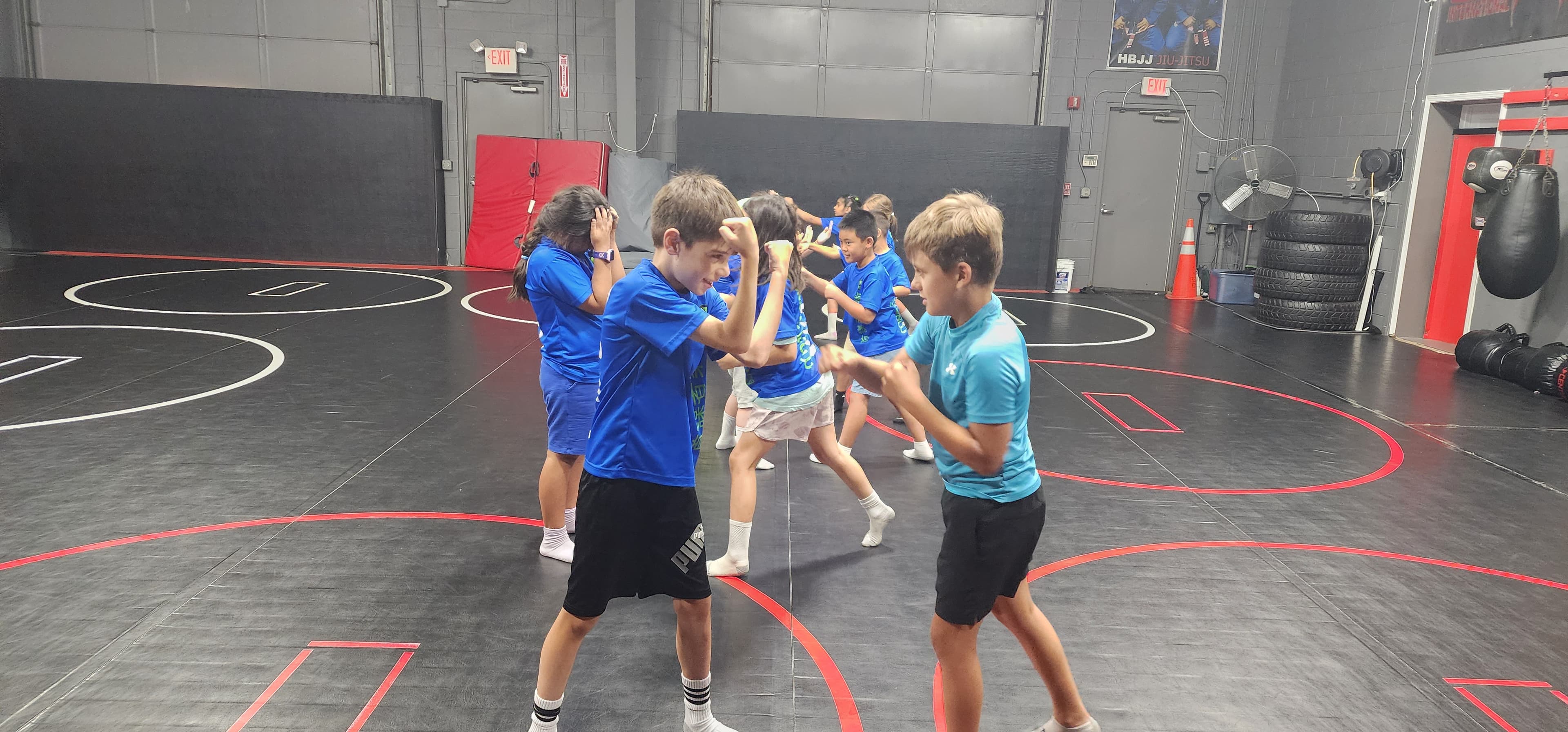 Campers practicing partner self-protection moves on the mats
